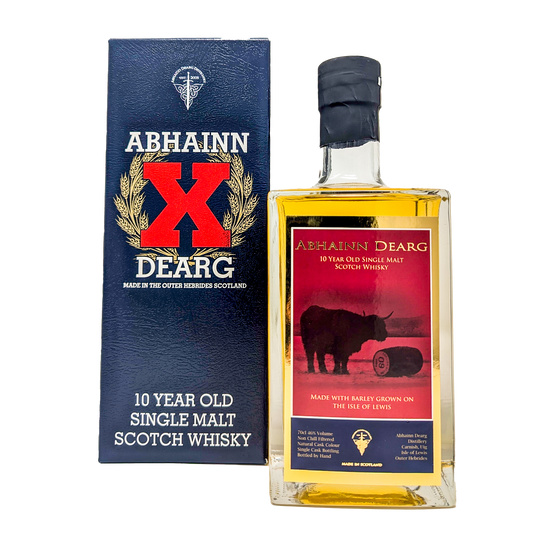 A bottle of the Abhainn Dearg 10 year old single malt whisky with its red and gold label with the highland cow and a cask of abhainn dearg beside the navy blue carton with the big bright red X on it