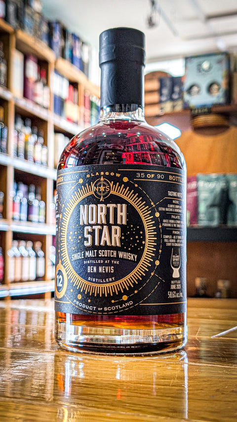 A bottle of North Star Ben Nevis 12 yo independent bottling exclusive to the Island Spirit Whisky Shop. The bottle is sat on a wooden work top with shelves of whisky in the back ground. The label is black with North Stars gold compass logo in the centre, the Island Spirit Whisky Shop logo can be seen in the bottom right of the label. 