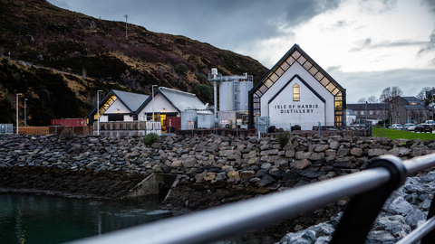 The isle of harris distillery in tarbert with a moody sky and lights on in the distillery 